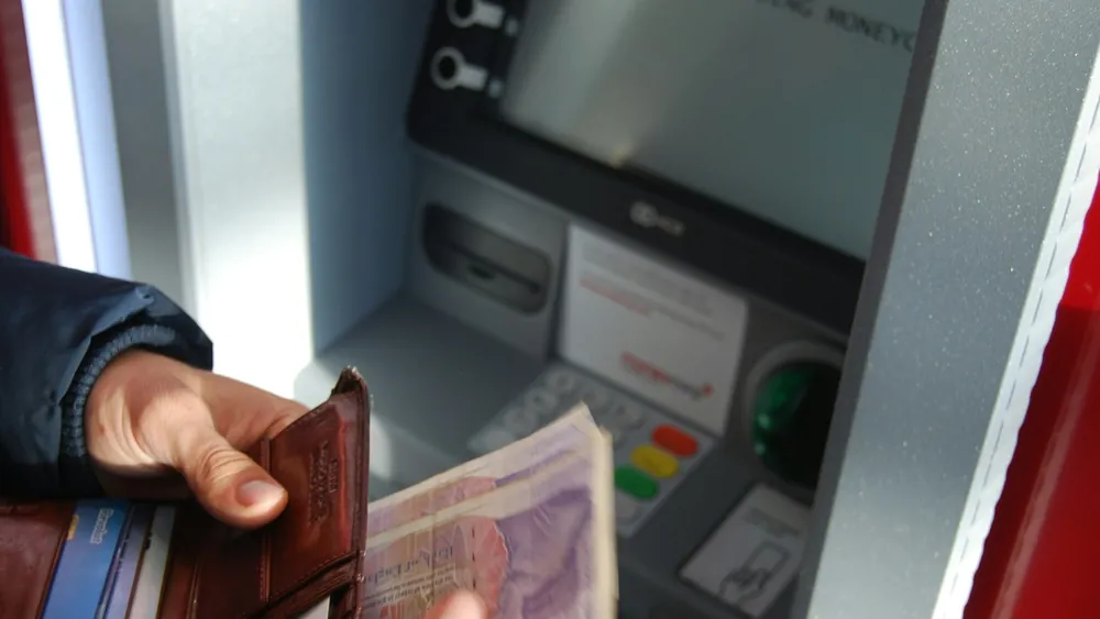 ATM 앞에서 지갑과 지폐를 든 손